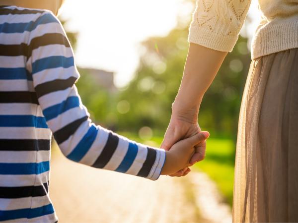 A child holding an adult's hand on a walk